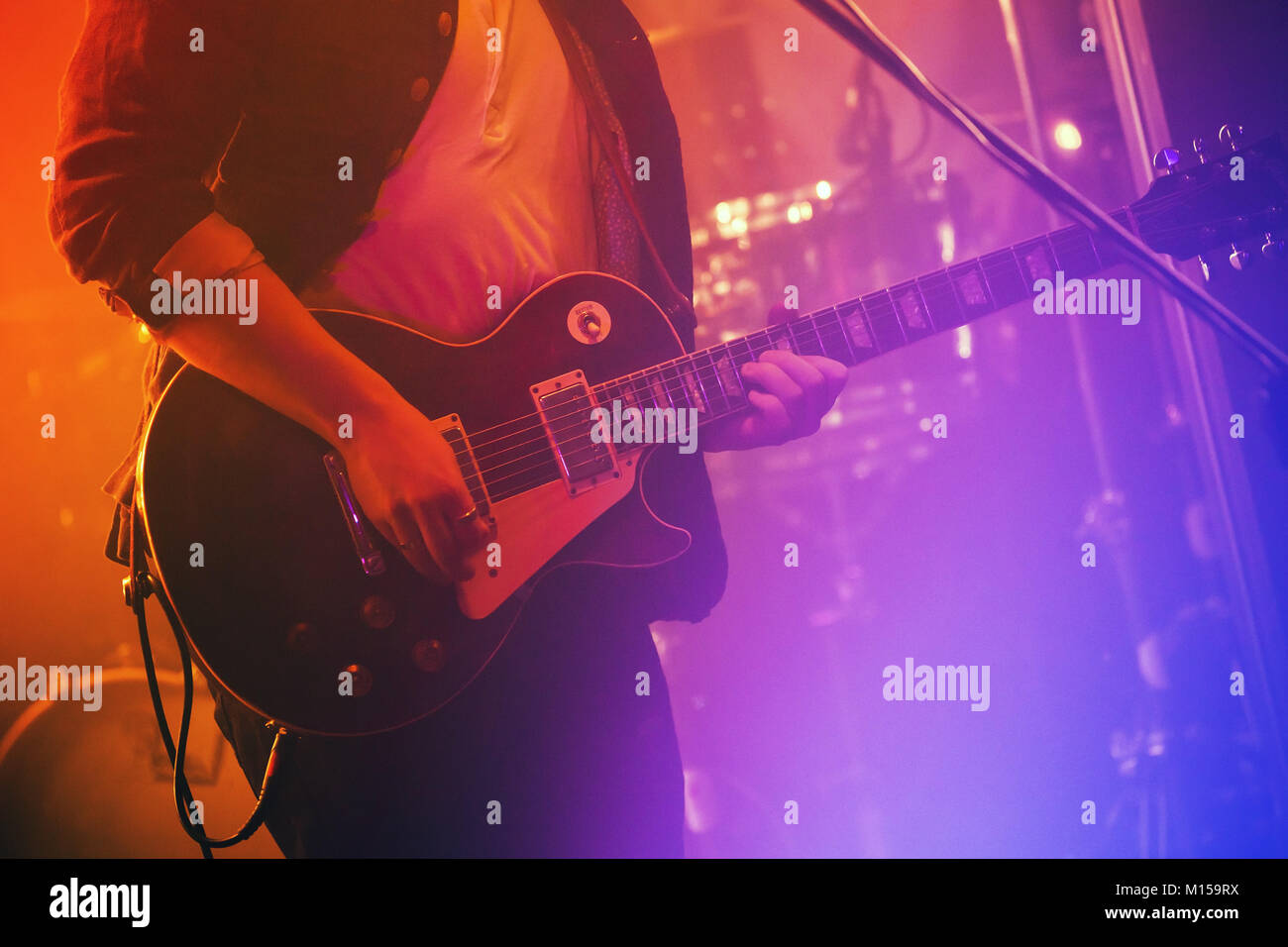 Electric guitar player plays on a stage with colorful scenic illumination, soft selective focus Stock Photo