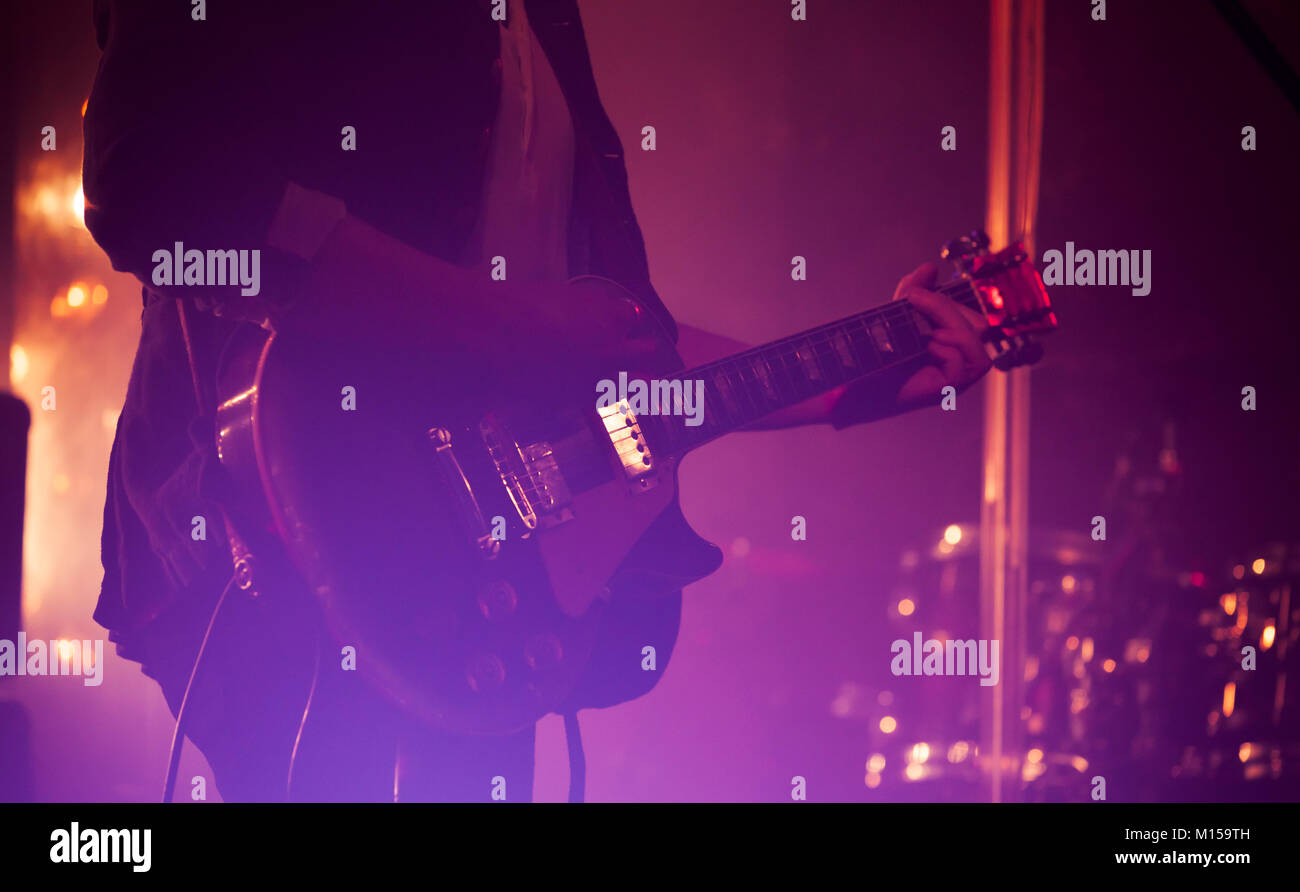 Electric guitar player on a stage with colorful scenic illumination, soft selective focus Stock Photo