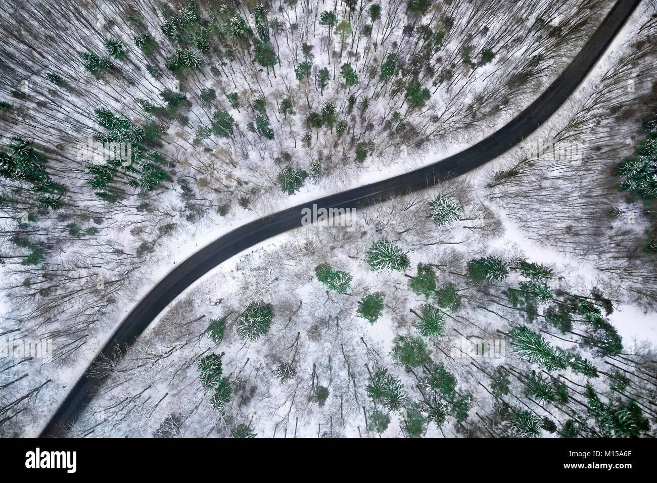 Aerial view of winter road in snowy forest. Drone captured shot from above. Stock Photo