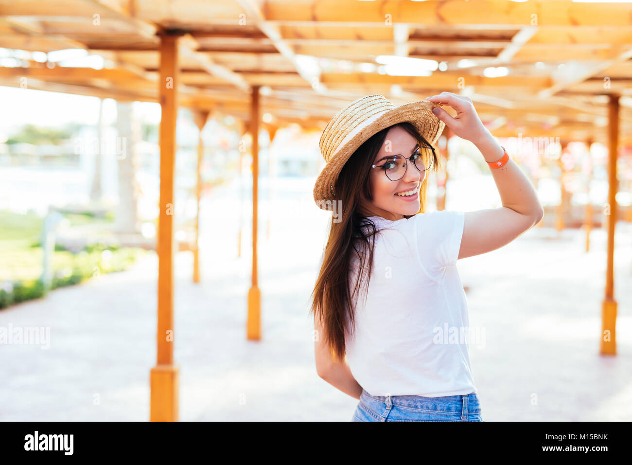Young beautiful happy woman hipster in a hat and sunglasses stands on ...