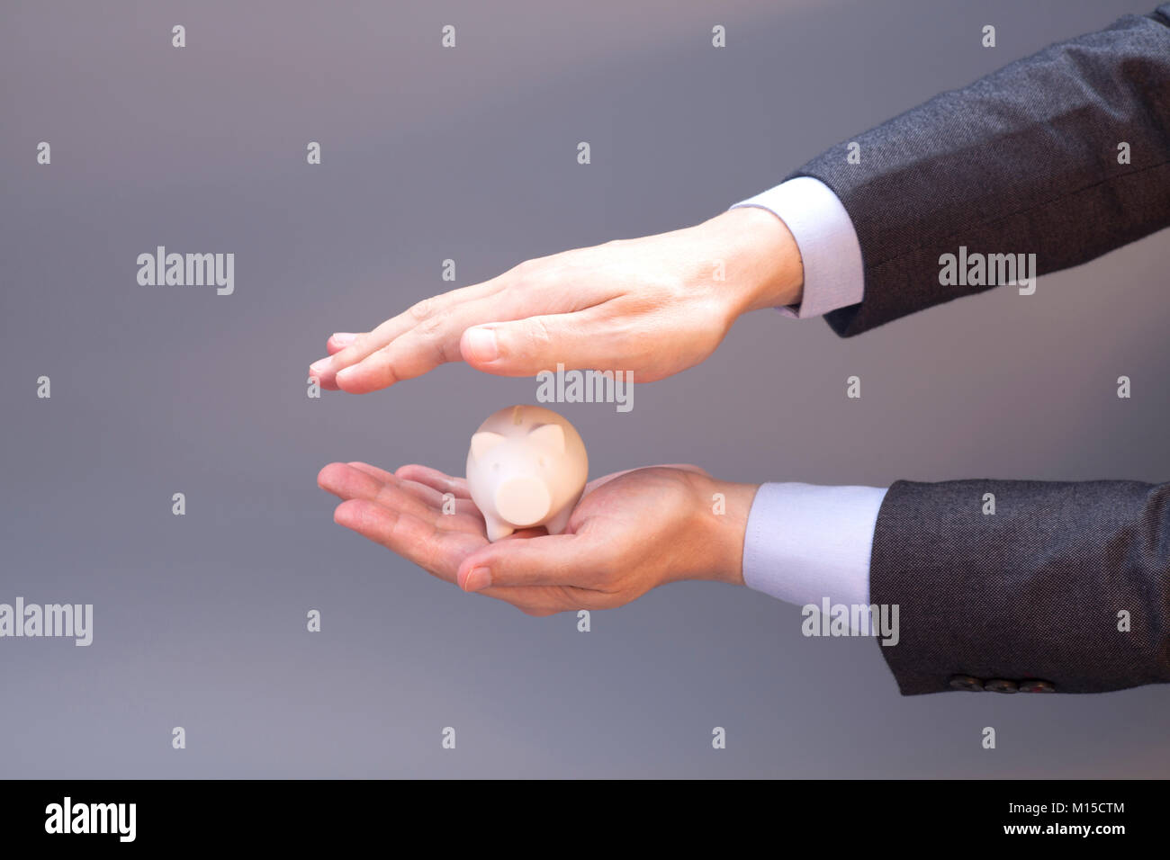 Business Man Holding Piggy Bank On Gray Stock Photo - Alamy