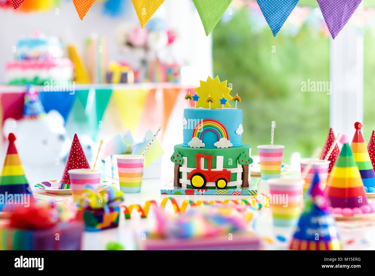 Kids birthday party decoration. Colorful cake with candles. Farm and transportation theme boys party. Decorated table for child birthday celebration.  Stock Photo