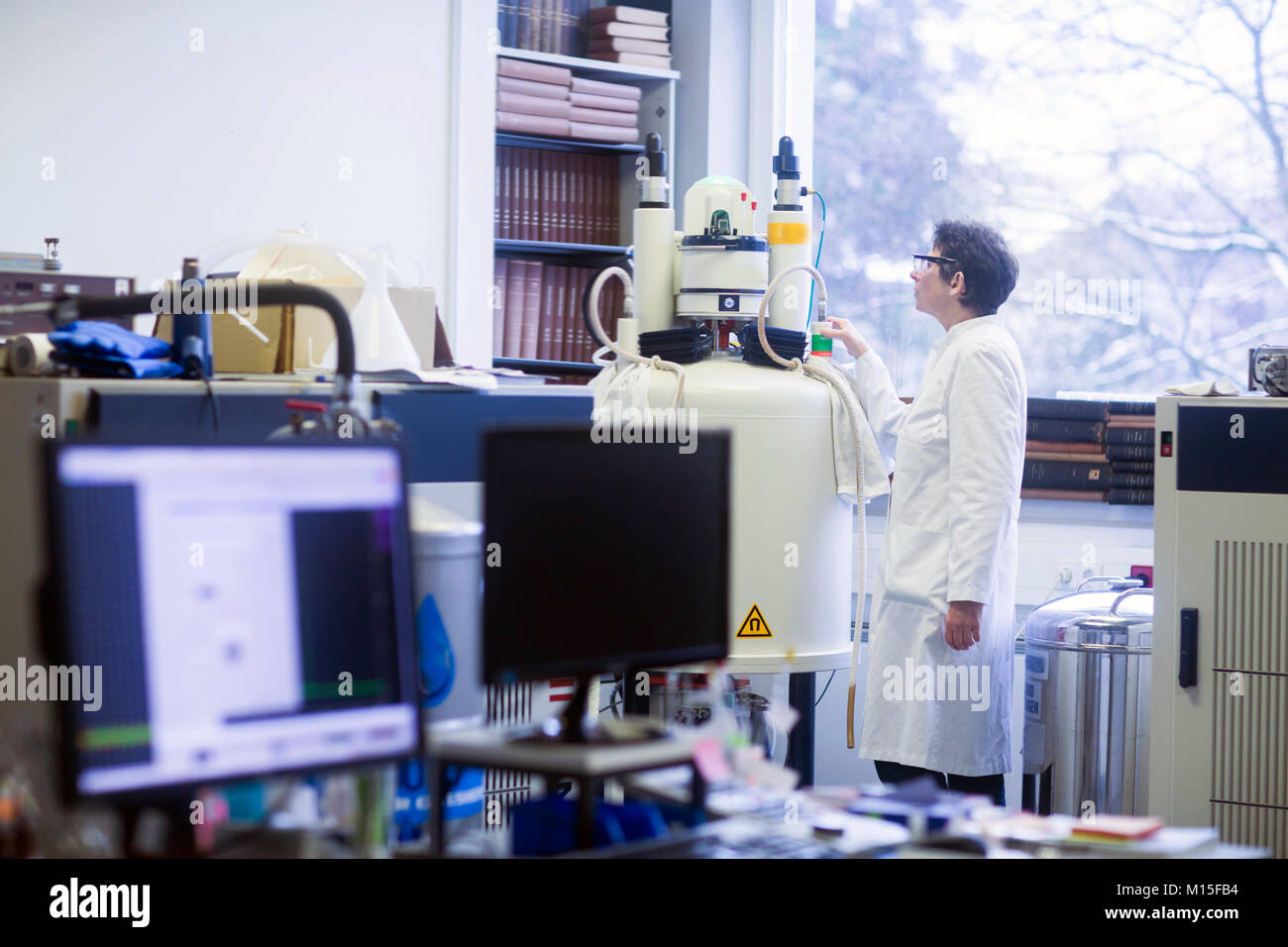 Chemist using an NMR (nuclear magnetic resonance) spectrometer in a pharmaceutical laboratory. Stock Photo