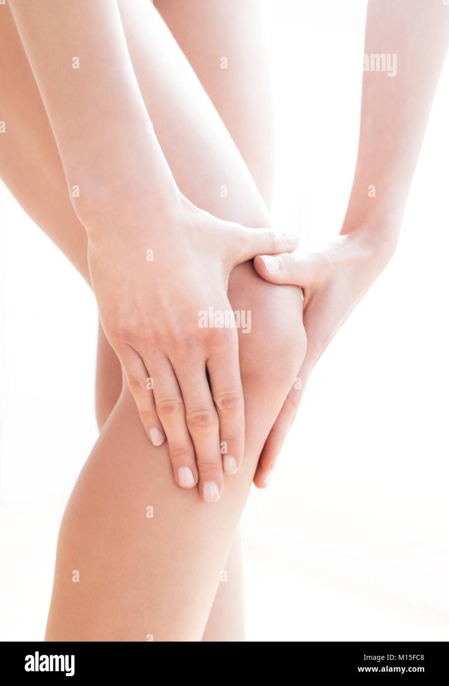 MODEL RELEASED. Young woman in pain rubbing her sore knee. Stock Photo