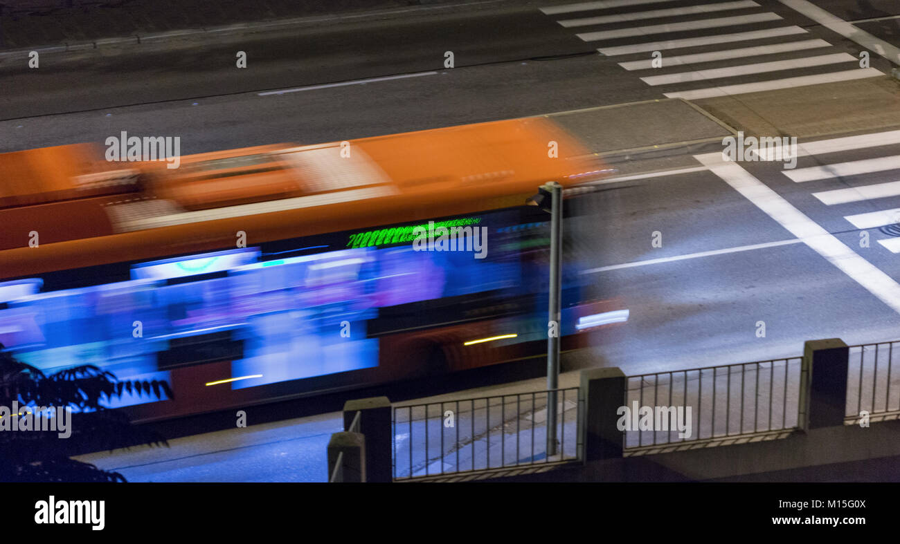 blurred bus moves on city street at night Stock Photo