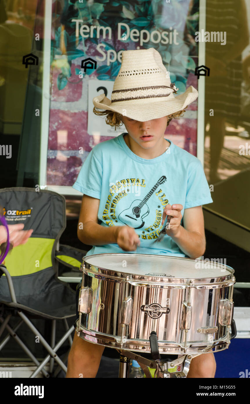 Young boy wearing a straw cowboy hat and blue t shirt beating a drum at Tamworth Country Music Festival 2018. Stock Photo