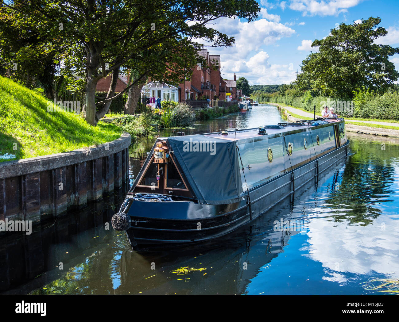 A narrowboat turns a sharp corner on a canal. Stock Photo