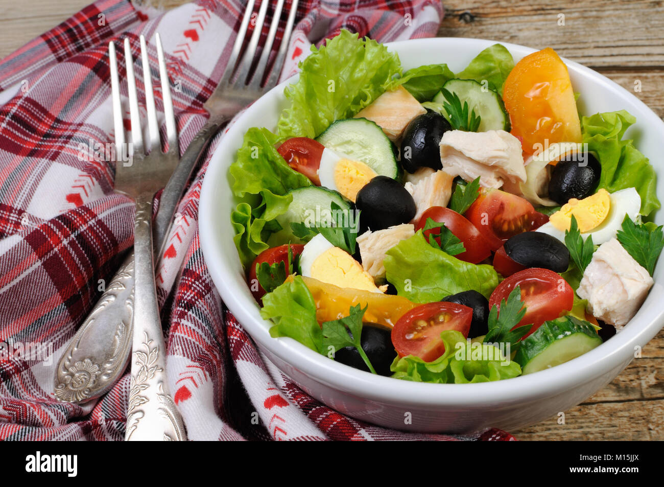 Vegetable salad with chicken and eggs, olives in lettuce leaves. Horizontal shot. Stock Photo