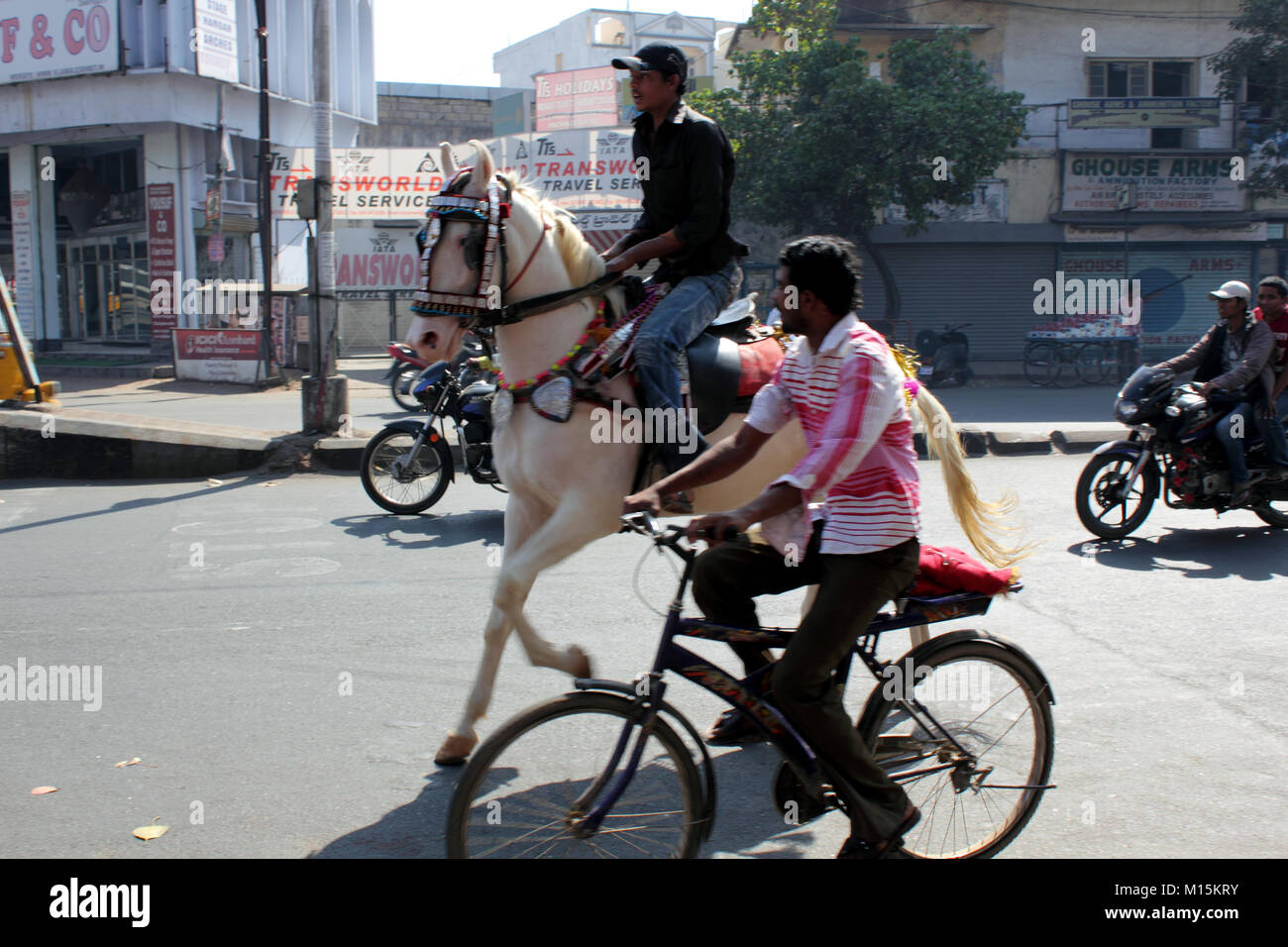 Indian man riding horse on busy street in Hyderabad India Stock Photo