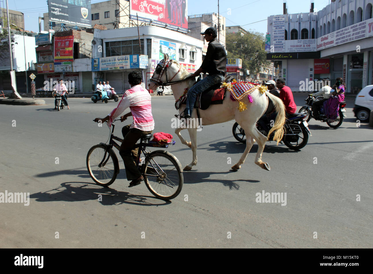 Indian man riding horse on busy street in Hyderabad India Stock Photo