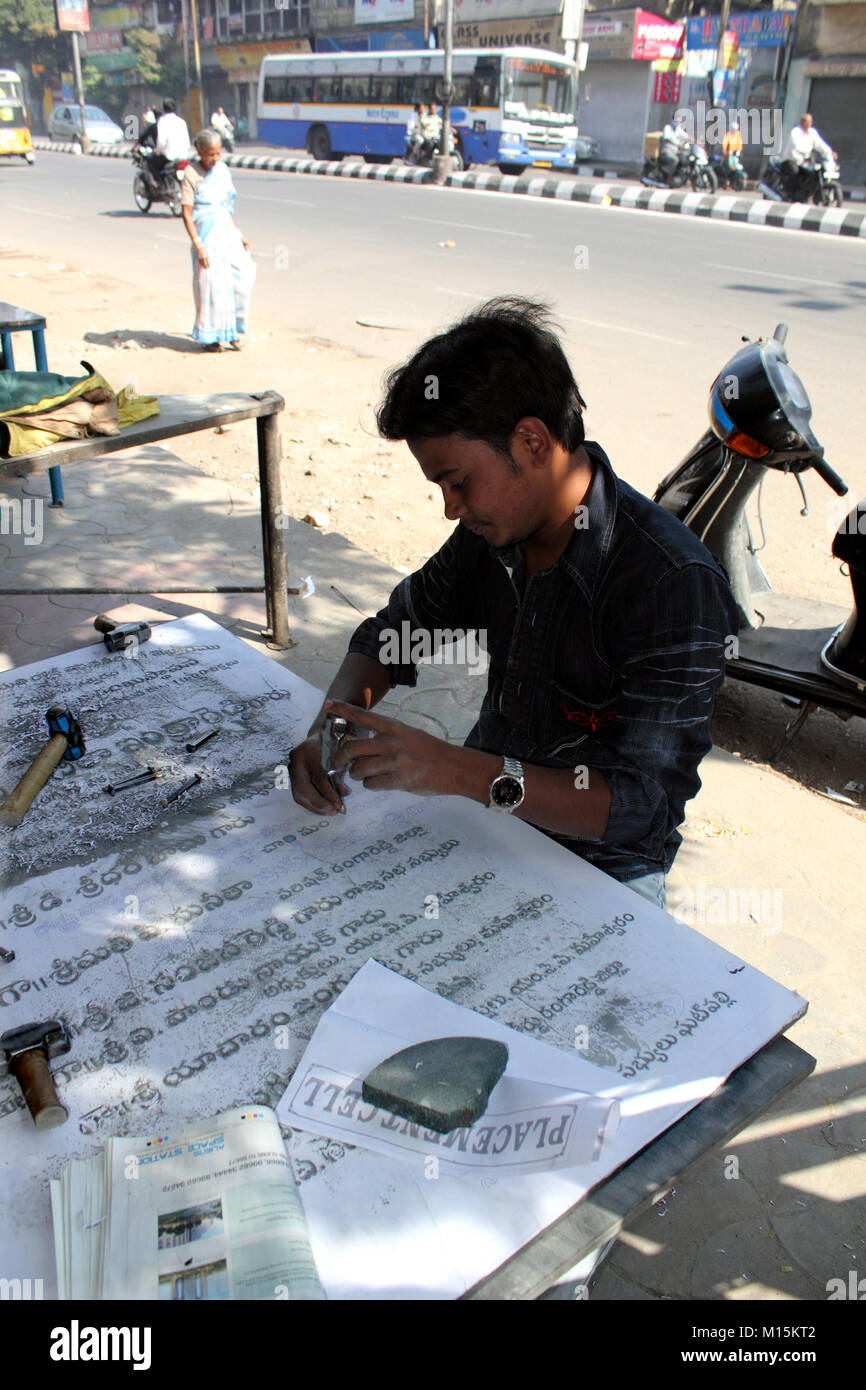 Indian stonemason carving letters on tablet in the street Stock Photo