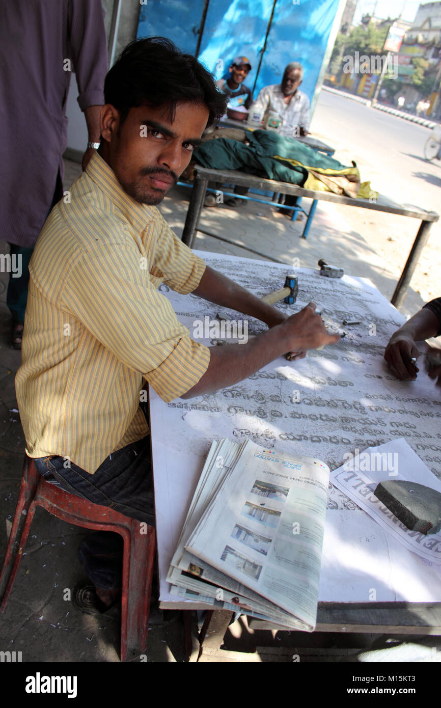 Indian stonemason carving letters on tablet in the street Stock Photo