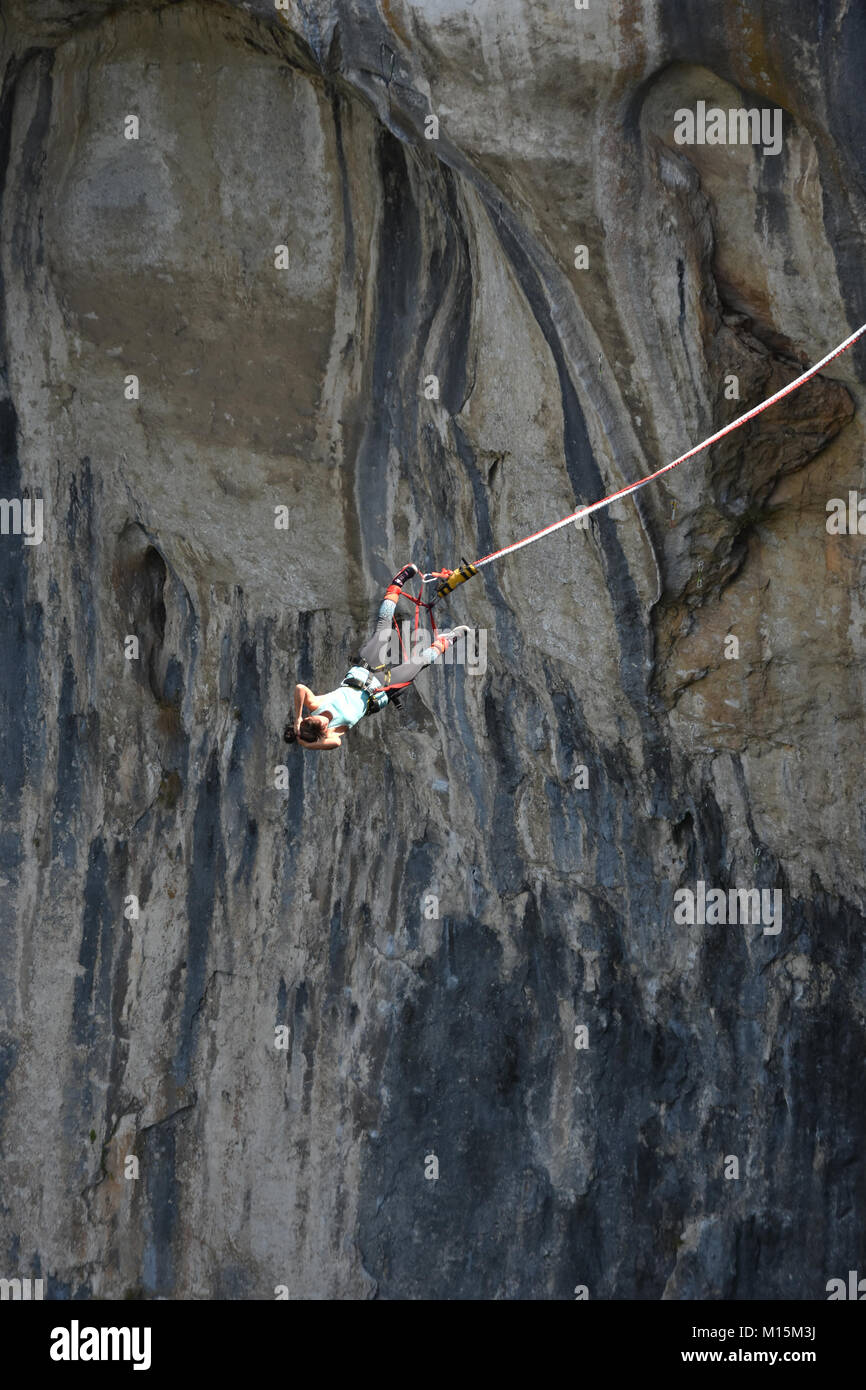 Young girl bungee jumper hanging on a cord, the dark rocks of Prohodna