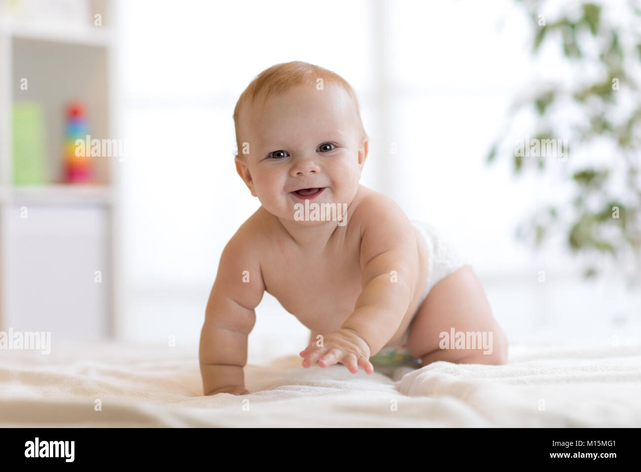 funny baby boy weared diaper crawling on bed at home Stock Photo