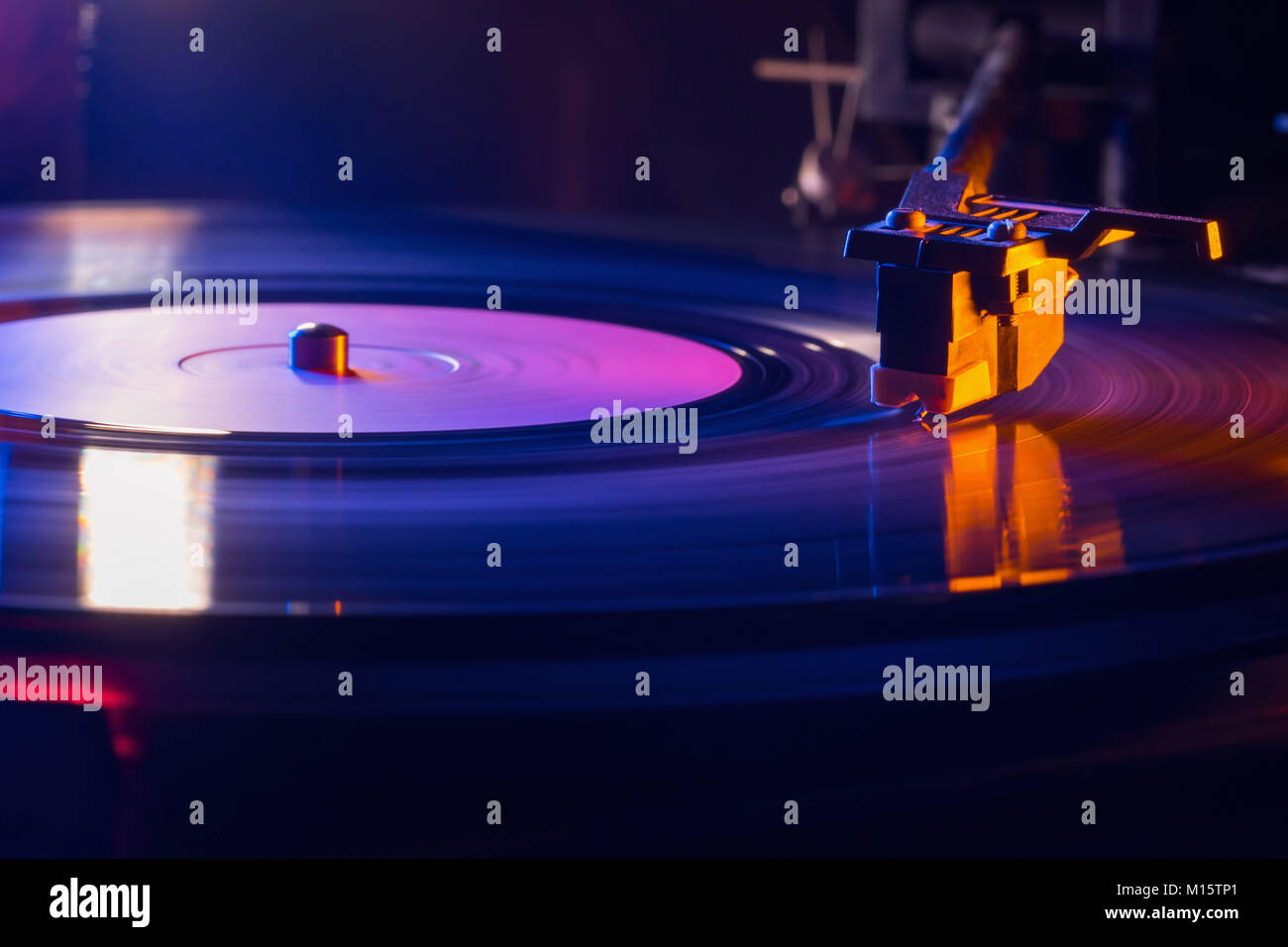 Retro-styled film look of a spinning record vinyl player. Close up. Side view. Colorful movie with neon light Stock Photo