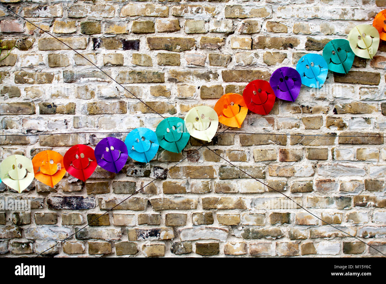 Symbol picture party,decoration,colorful garland with smiley faces on a brick wall Stock Photo
