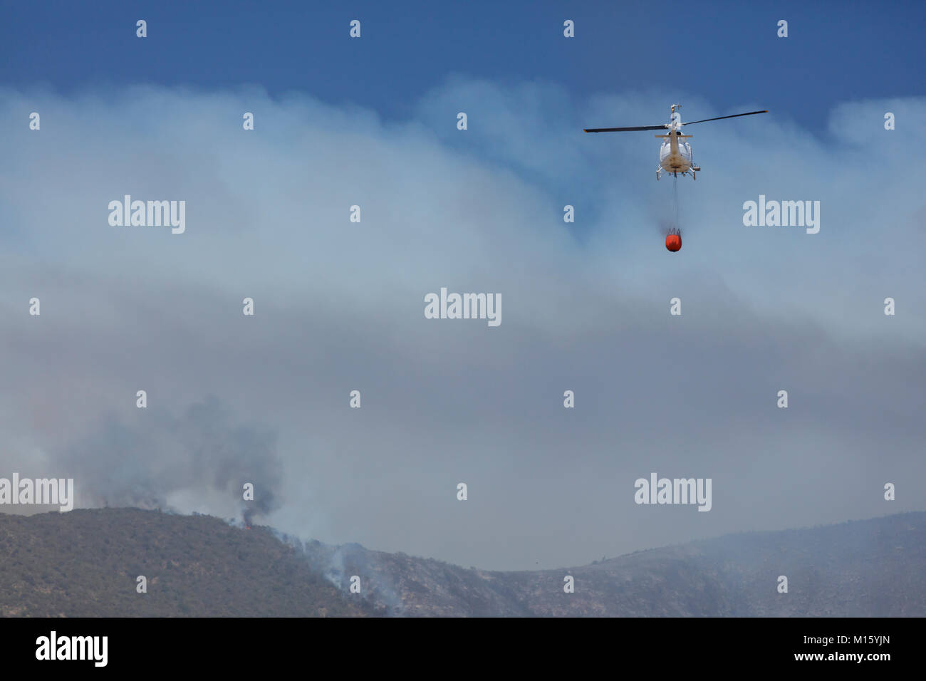 Helicopter flies with an extinguishing water tank to a fire,Los Molles,La Ligua,Valparaíso,Chile Stock Photo