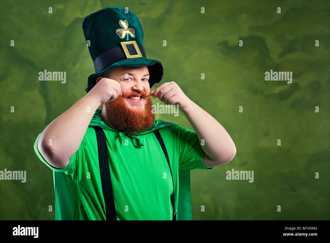 A fat man with a beard in St. Patrick's suit is smiling. Stock Photo