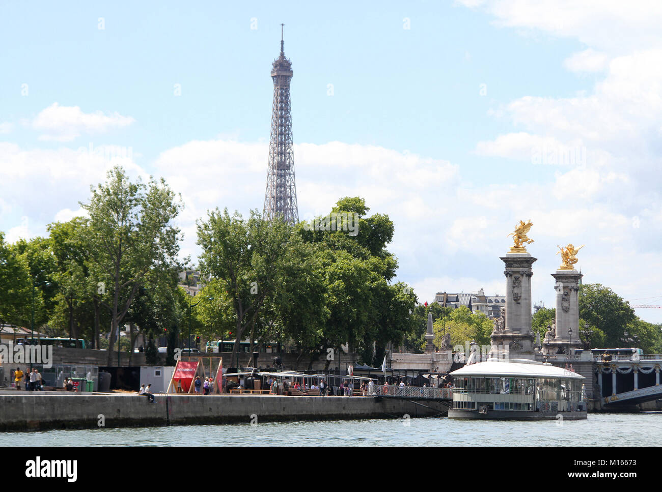 View of Eiffel Tower, Stationary floating restaurant tavern called Rosa Bonheur sur Seine and Gilded Fames sculptures on the socle counterweights on t Stock Photo