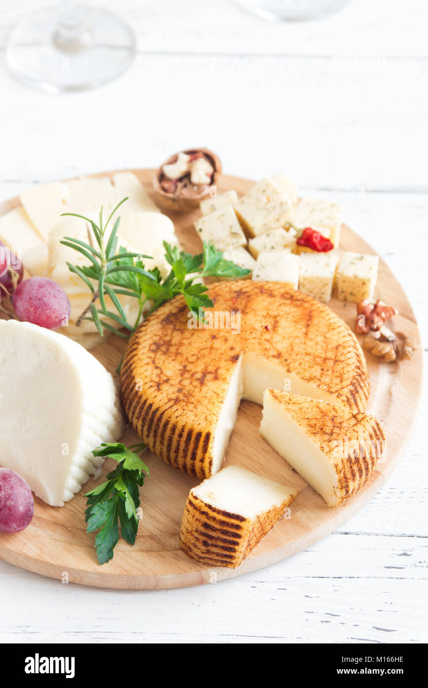 Cheese platter with assorted cheeses, grapes, nuts over white wooden