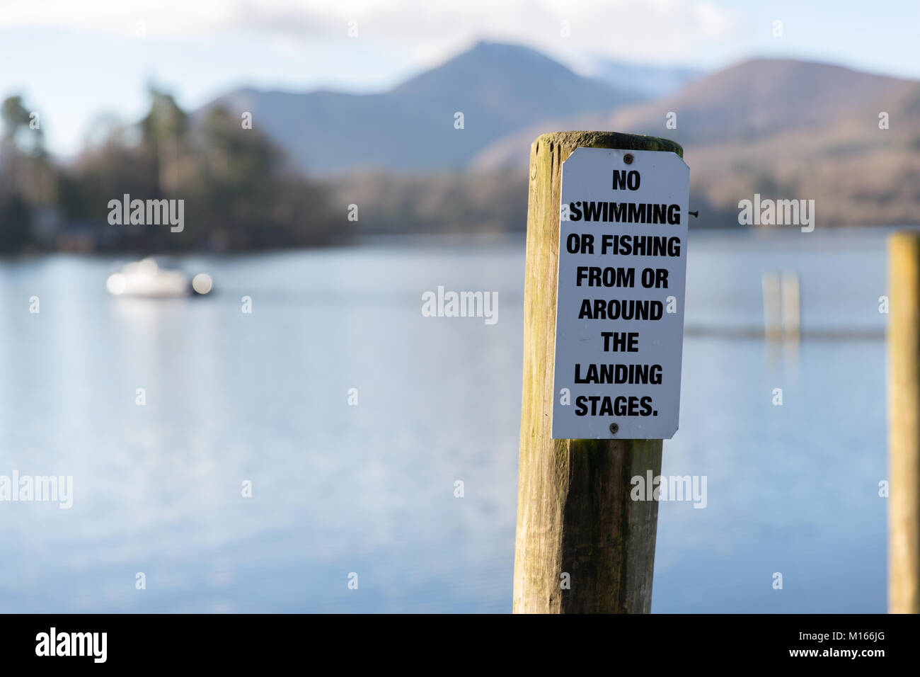 A No Swimming/Fishing warning sign on Derwent Water landing Stages near Keswick in the English Lake District National Park Stock Photo