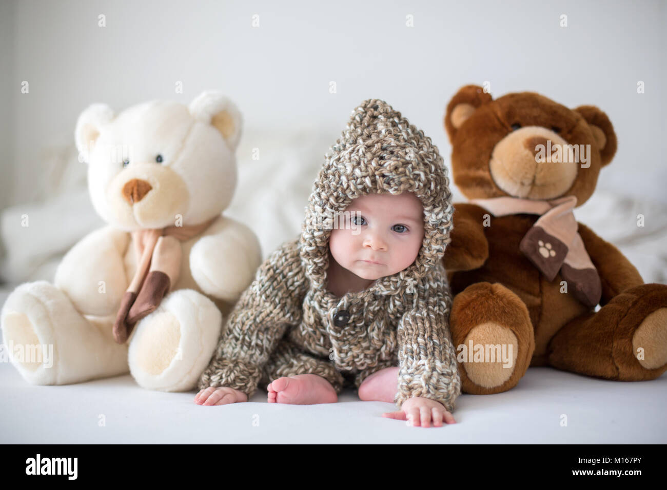 Little baby boy playing at home with soft teddy bear toys, sitting in ...