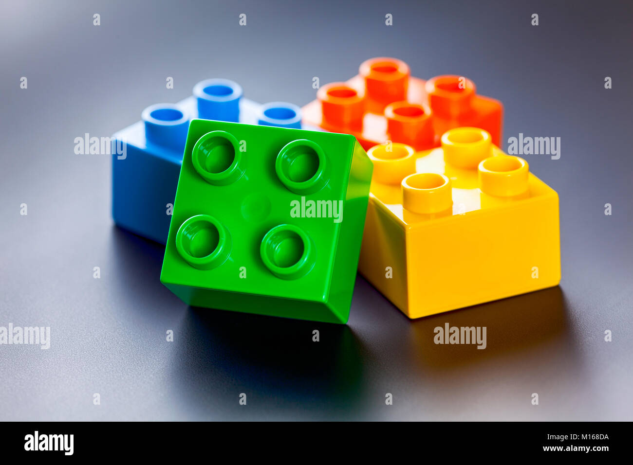Four colorful plastic toy building blocks on gray background Stock