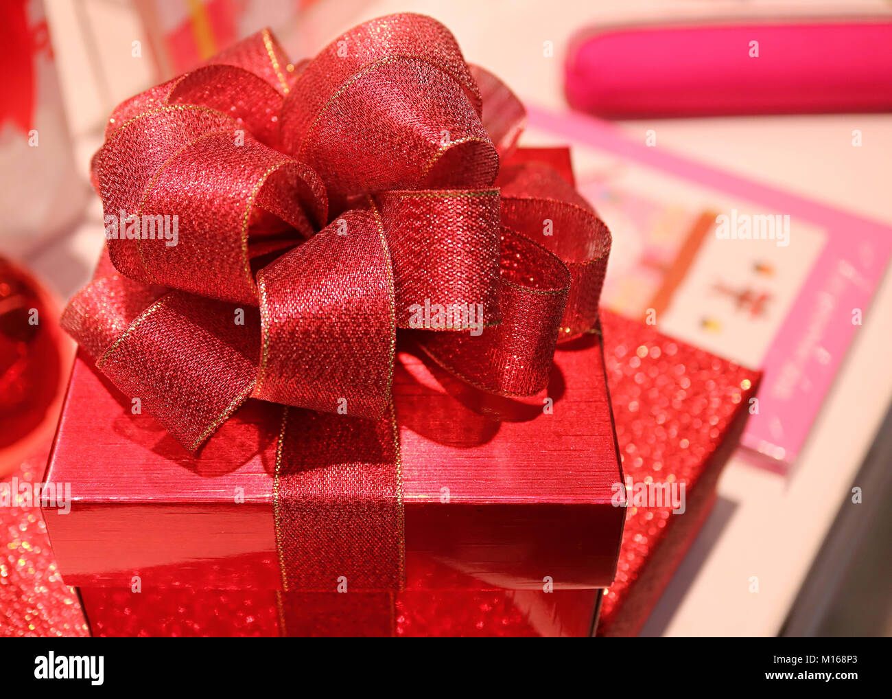 Closed up square shiny red gift box with gritter red ribbon bow ...