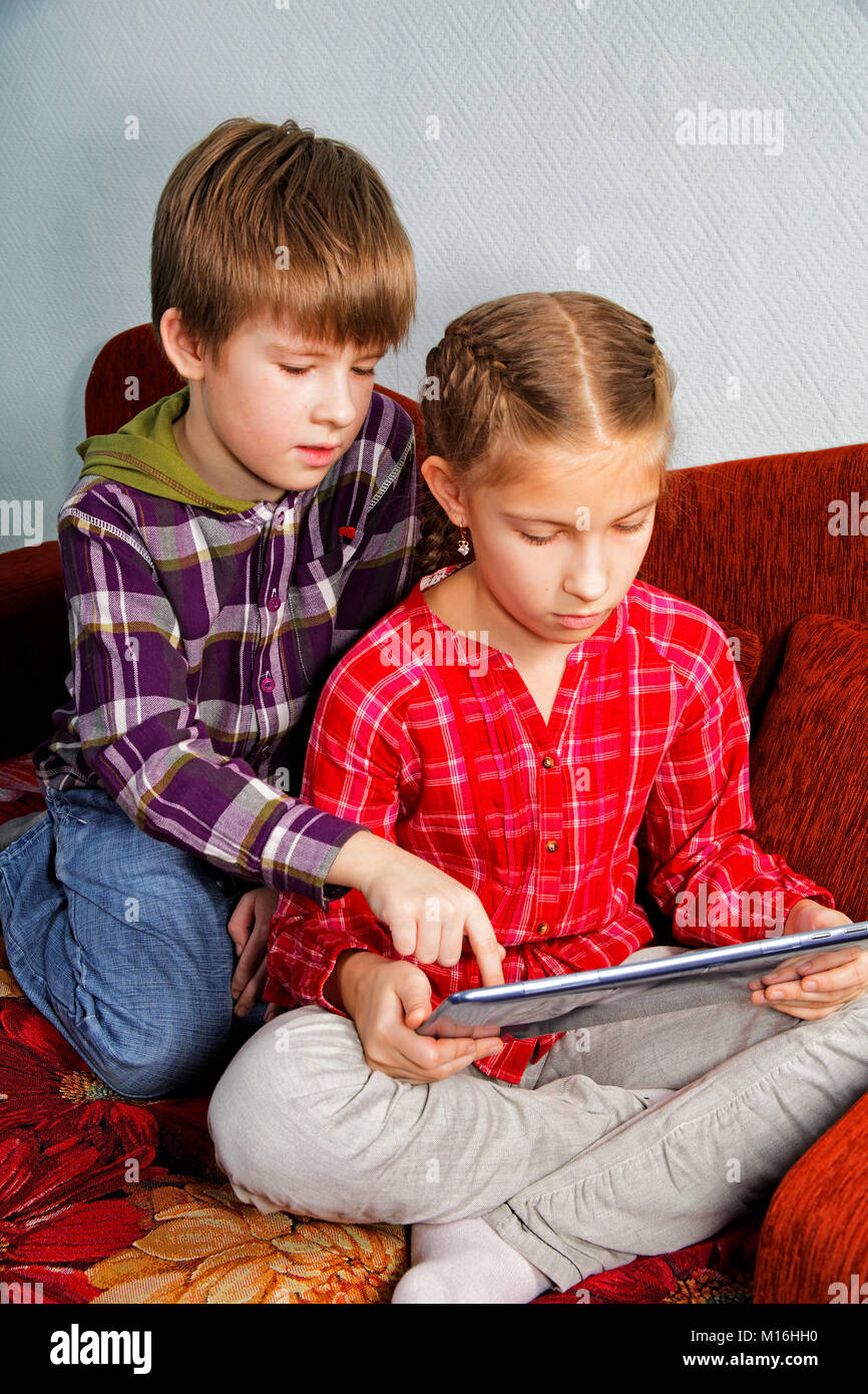 The boy teaches his sister to use the electronic tablet Stock Photo