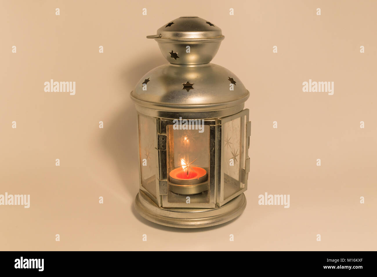 Golden lantern with a lighted candle inside on dark background with