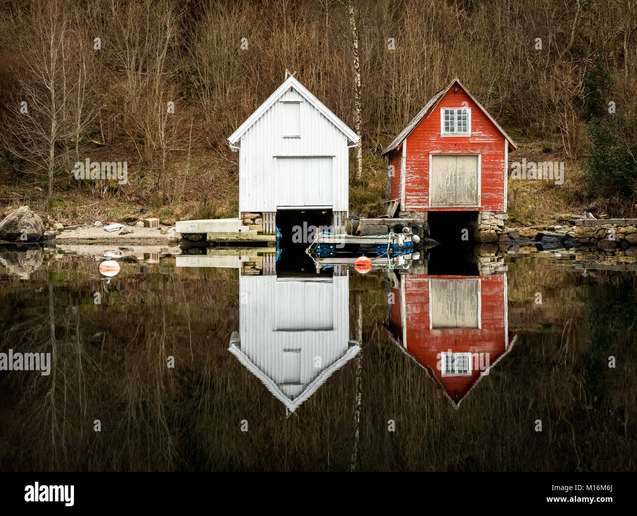 Kolnes in Norway - januray 10, 2018: Two old wooden boathouses reflected in the calm ocean. Norwegian west coast, Norway Stock Photo