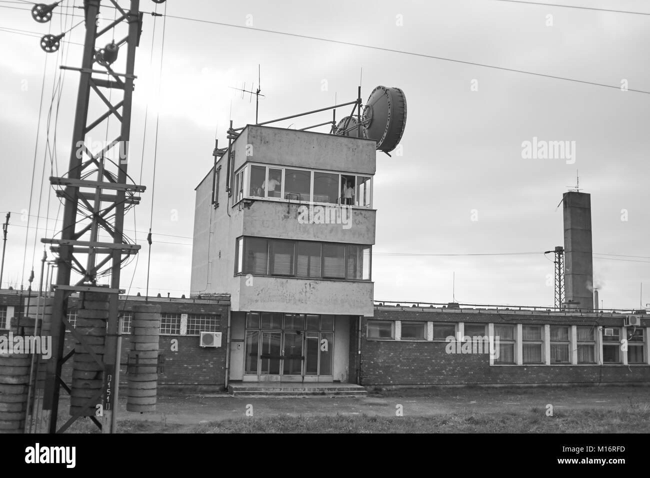 A soviet era communications station next to the rail lines in rural Hungary with two workers in the window Stock Photo