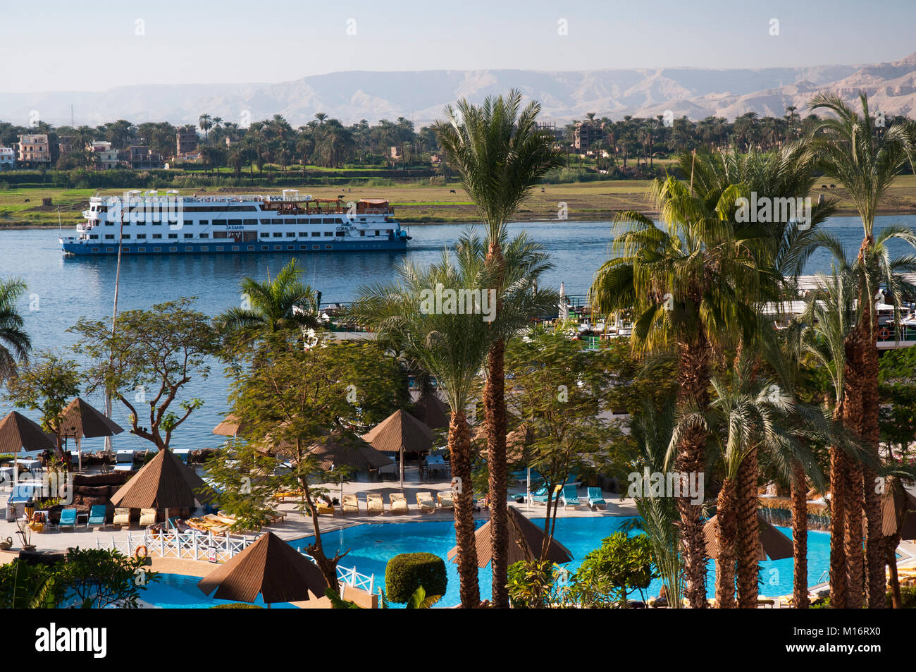 Coral Sea Nile Cruises' vessel Jasmin sails past the Pyramisa Isis Hotel on the Nile at Luxor, Egypt Stock Photo