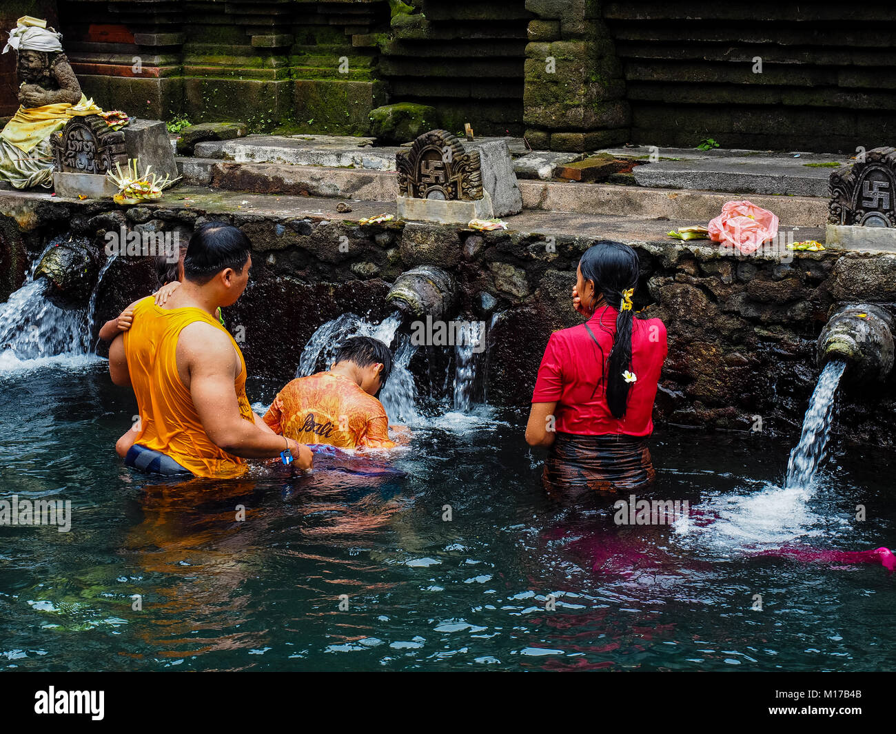 Balinese family praying and bathing at Pura Tirta Empul - a hindu famous temple in Bali Stock Photo