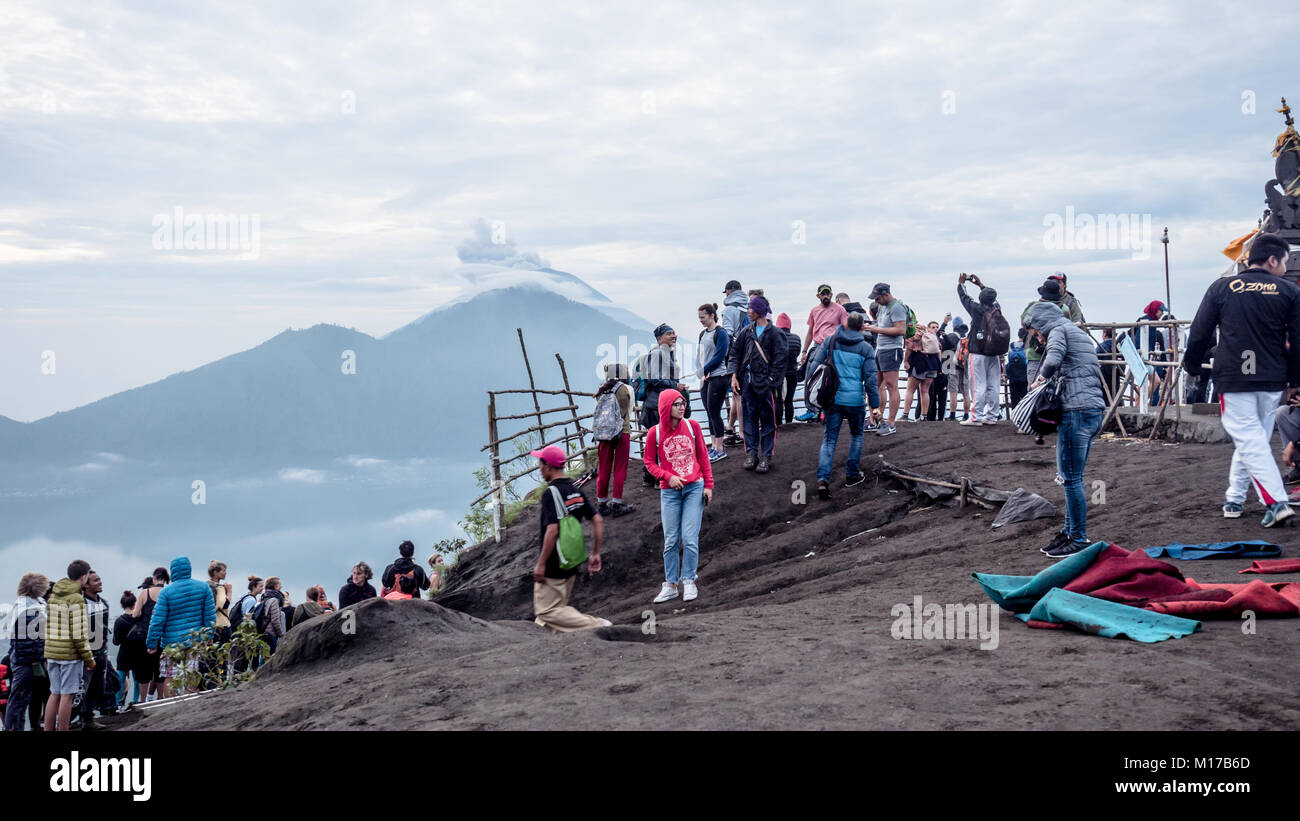 Crowds of people gather on top of Mount Batur - a popular daily tradition of enjoying the sunset while watching eruption on mount Agung active volcano Stock Photo