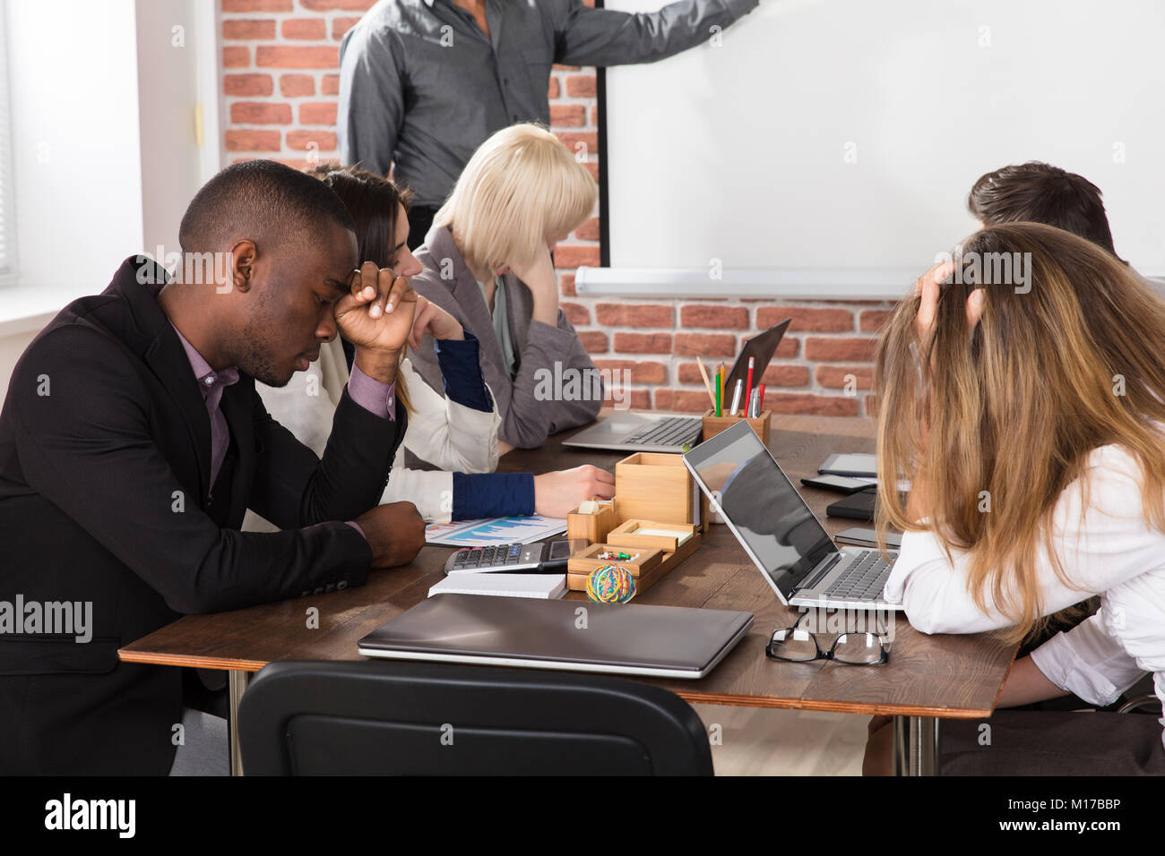 Diverse Tired Young Businesspeople Bored During Meeting In Office Stock