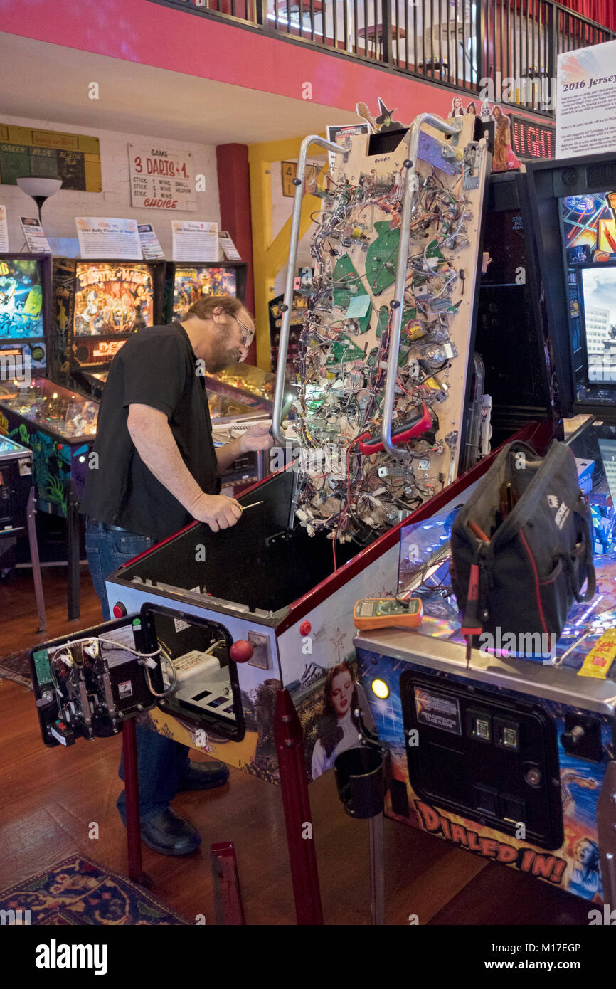 An electronic technician repairs the wiring on a vintage 1970's pinball game at the Silverball Museum in Delray Beach, Florida, USA. Stock Photo