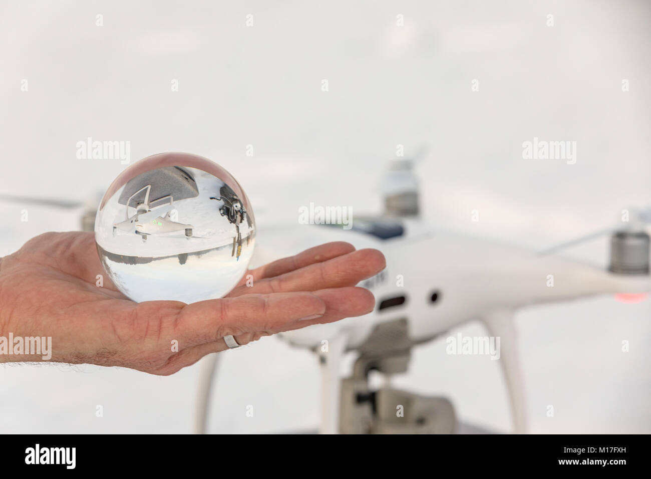 The white drome is mirrored in a crystal ball. Crystal ball in hand and white dron in ball. Stock Photo