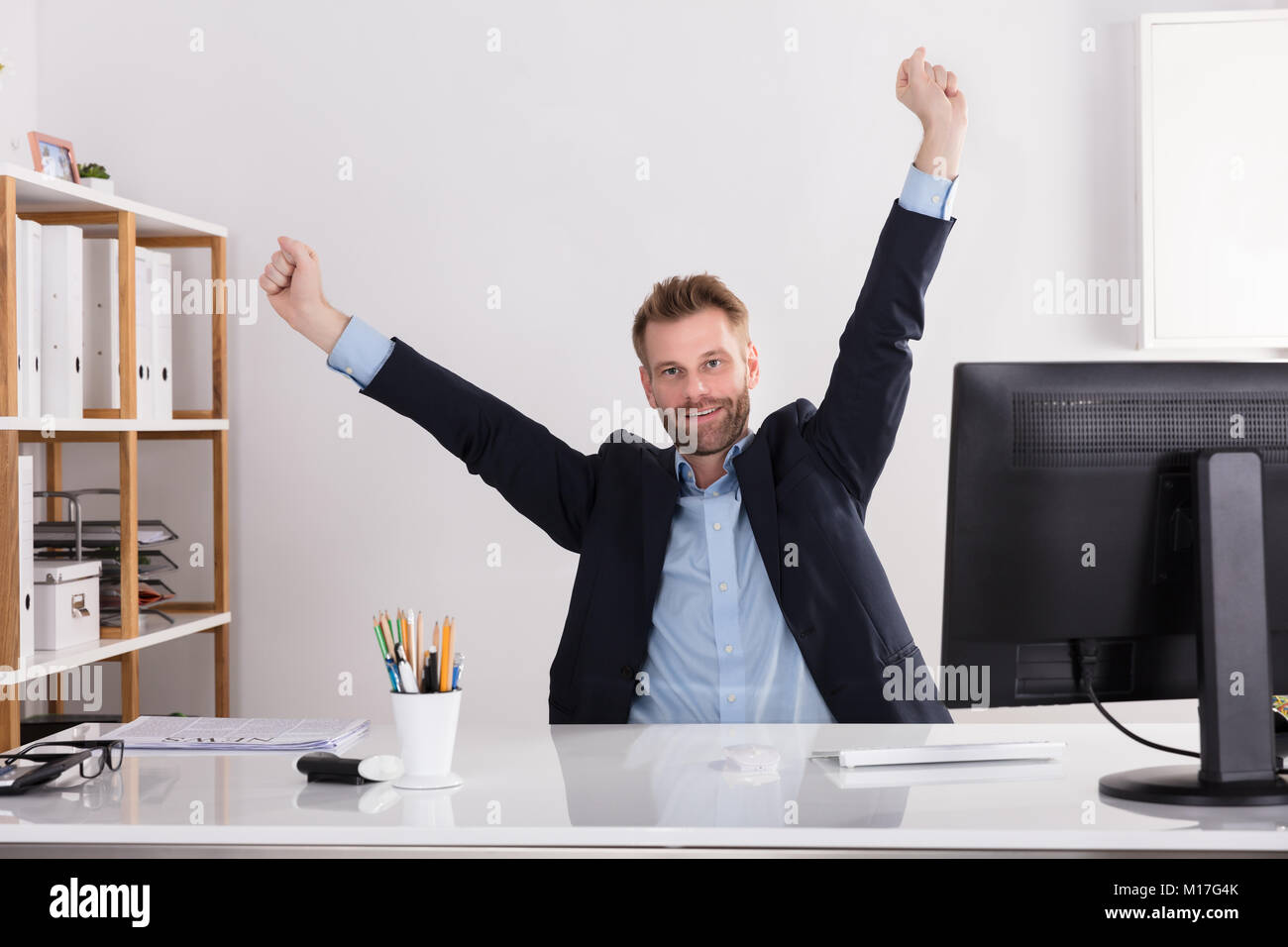 Happy Young Businessman Raising His Arms Sitting In Office Stock Photo ...