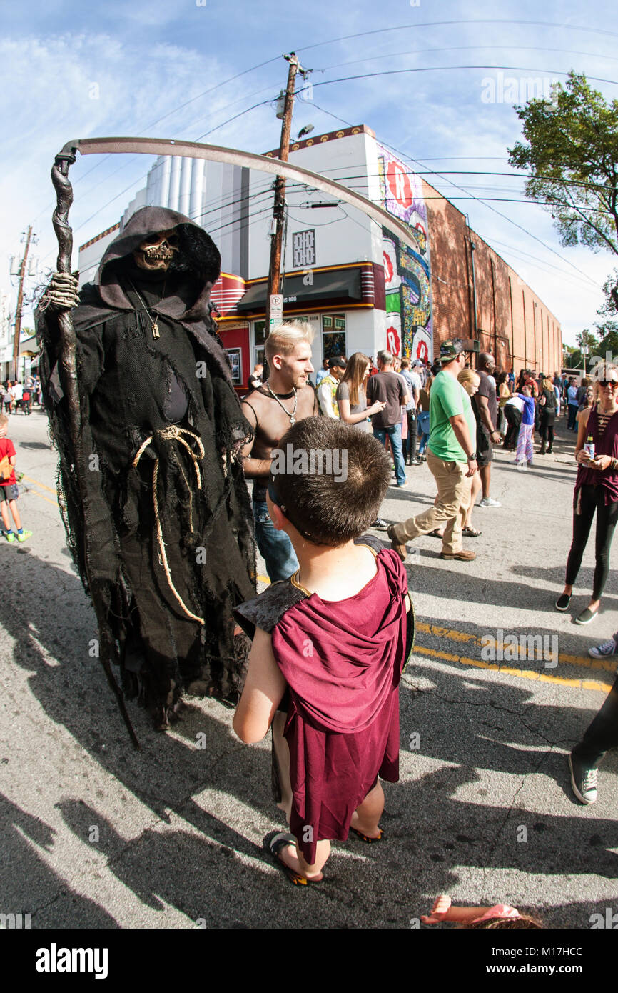 Atlanta, GA, USA - October 21, 2017:  A boy interacts with person wearing menacing grim reaper costume and holding scythe at Atlanta Halloween parade. Stock Photo