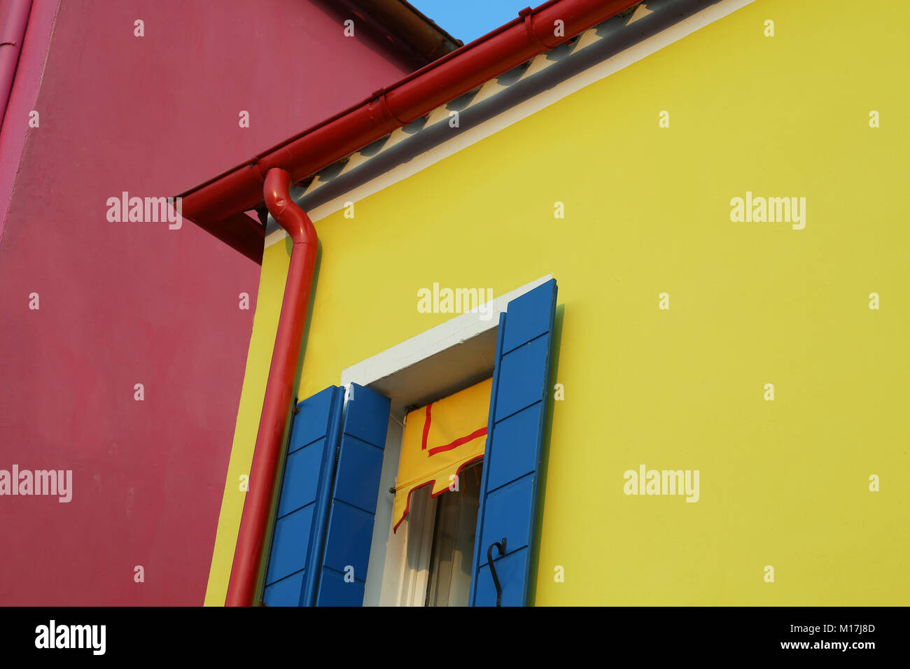 yellow house with red gutters and blue balconies in the island of Burano near Venice in Italy Stock Photo