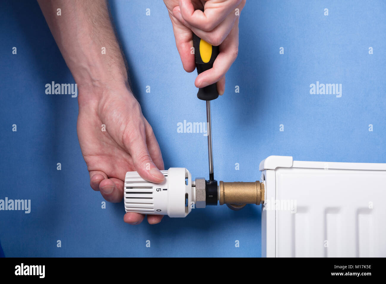 Close-up Of A Human Hand Installing Radiator With Screwdriver Stock Photo