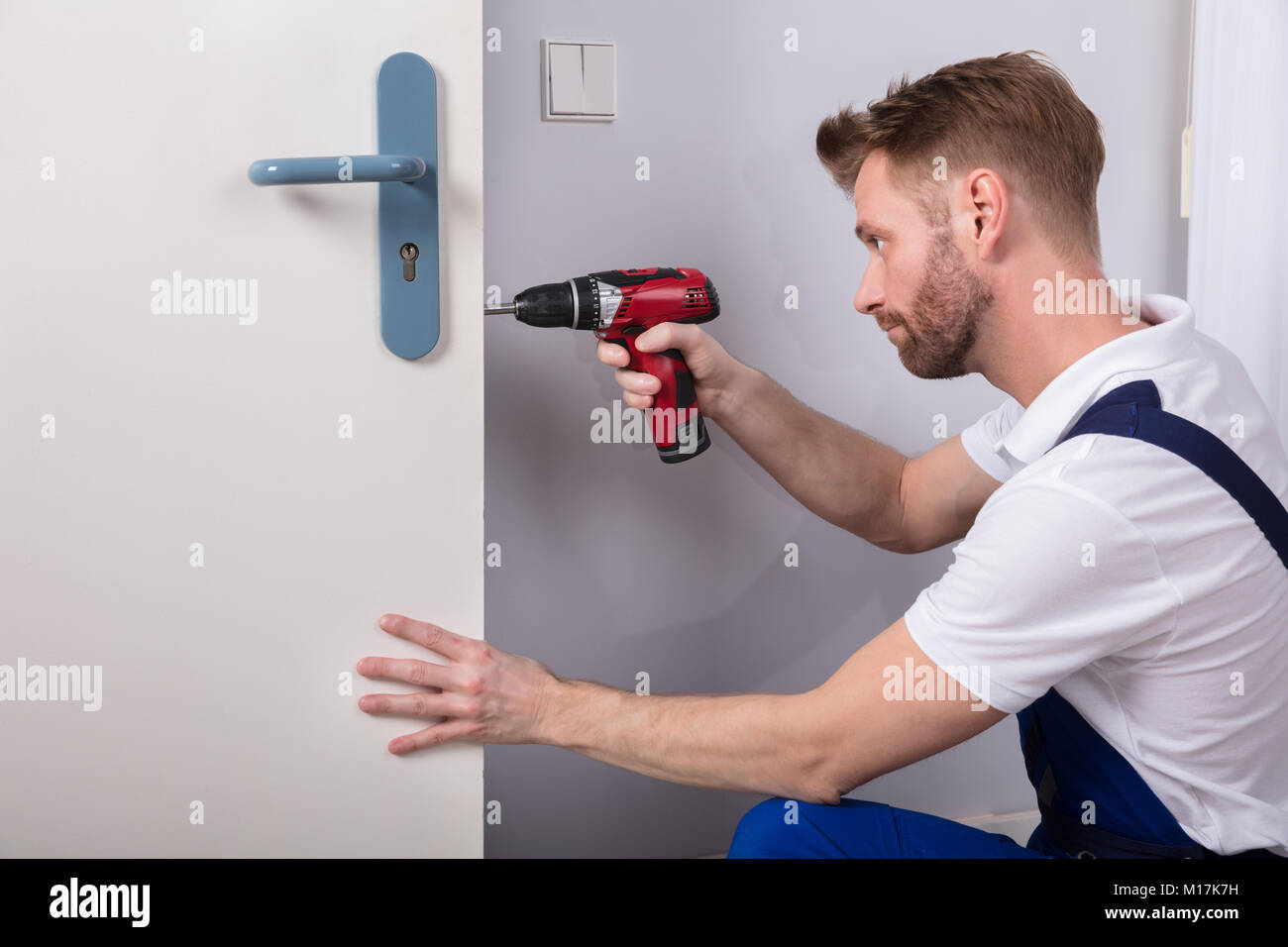 Young Carpenter Install Door Lock With Wireless Screwdriver Stock Photo Alamy