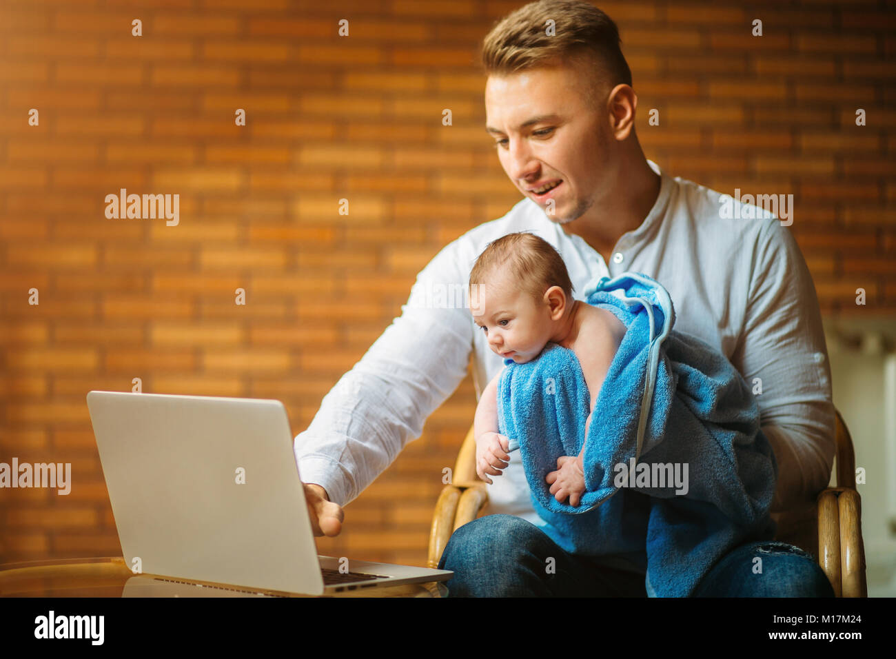 Father With Newborn Baby Working From Home Using Laptop Stock Photo - Alamy