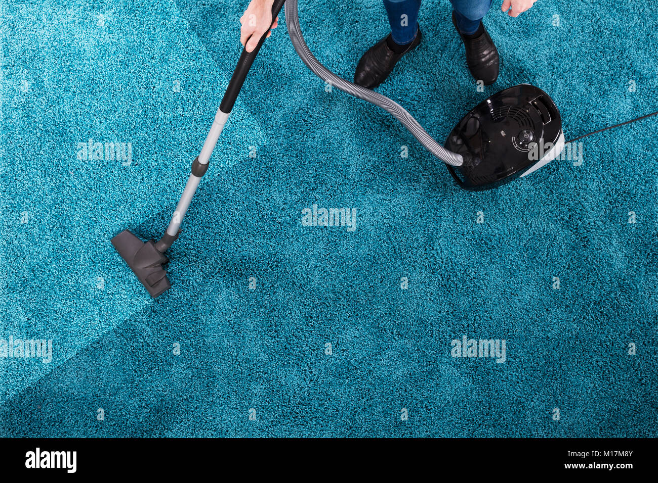 High Angle View Of A Person Cleaning Blue Carpet With Vacuum Cleaner ...