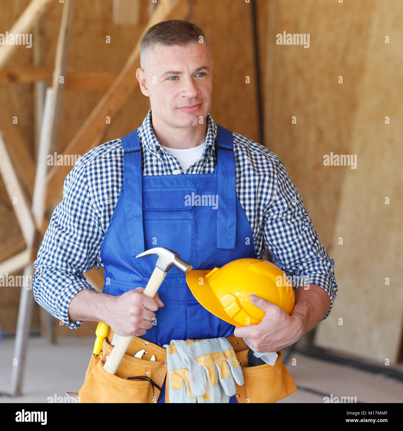 Portrait of construction worker at construction site holding hammer and ...