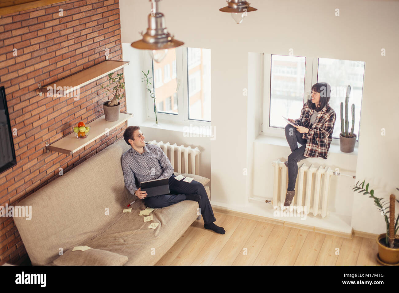 man and woman sitting back to back and doing their works Stock Photo