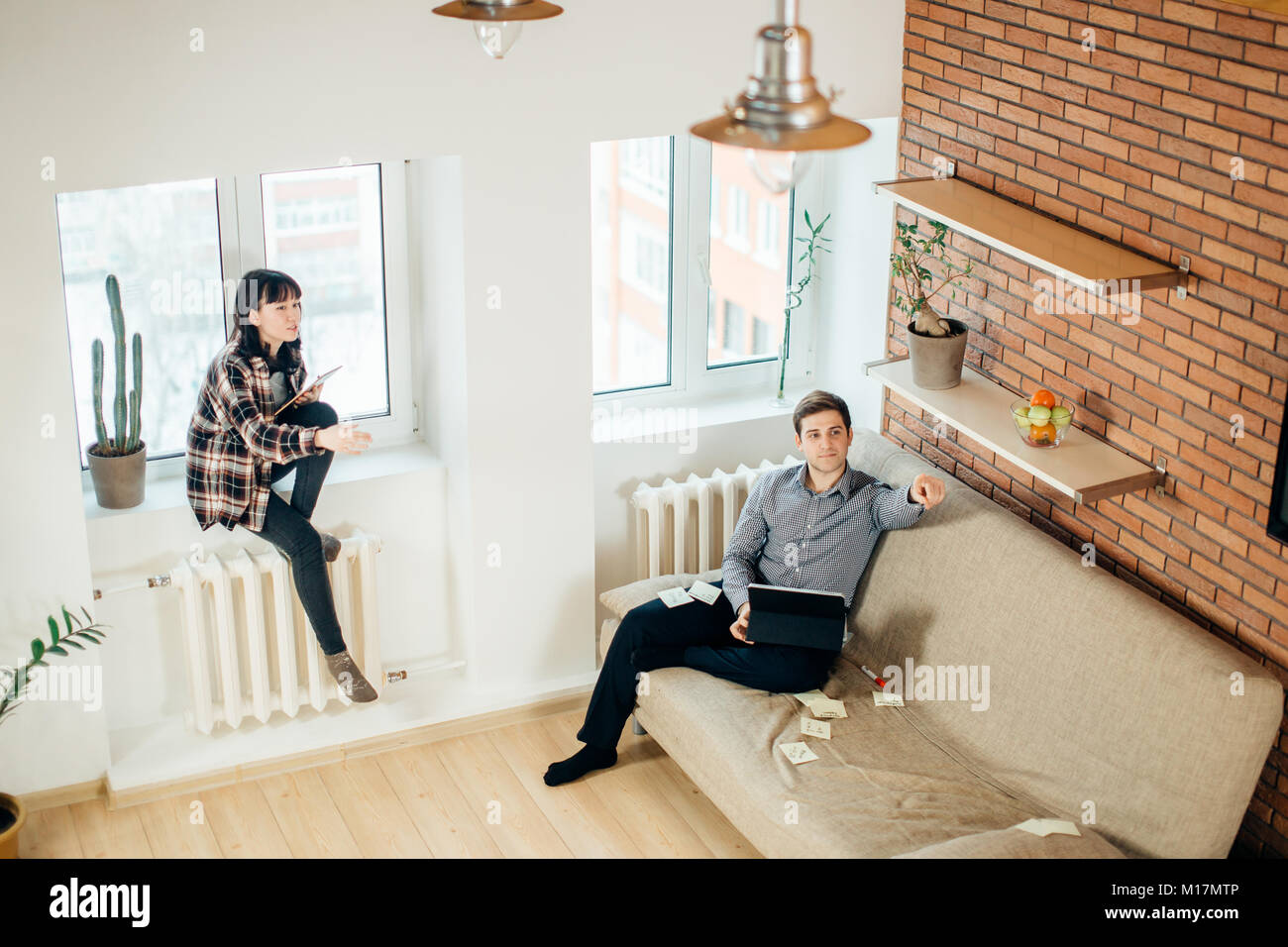 man and woman sitting back to back and doing their works Stock Photo