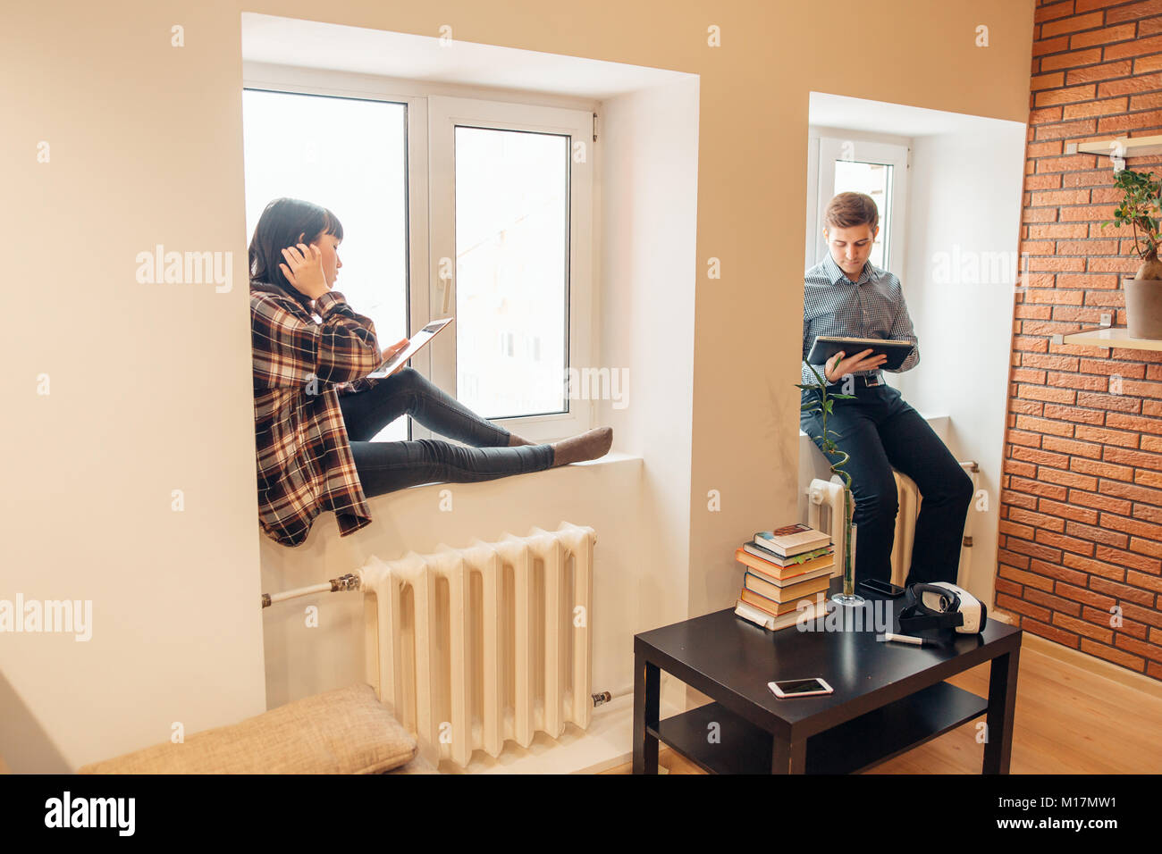 man and woman sitting back to back and doing their works Stock Photo