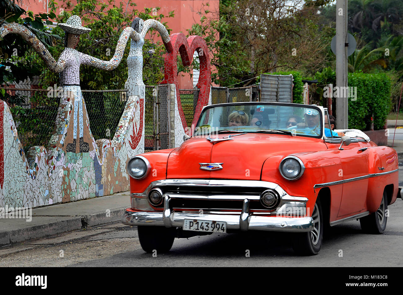 (180129) -- HAVANA, Jan. 29, 2018 (Xinhua) -- A vintage car passes a facade benefited by the community cultural project 'The Joy of Living' headed by the Cuban painter and sculptor Jose Antonio Rodriguez Fuster, in Jaimanitas of Havana, Cuba, on Jan. 25, 2018. Fusterland, a humble neighborhood to the west of Havana transformed from a remote fishing village, has become a hot tourist attraction in recent years thanks to the transformation, and the key to the fundamental change is, to the shock of many, art. Jaimanitas, or what many people call 'Fusterland,' owns its unusual popularity to Cuban p Stock Photo